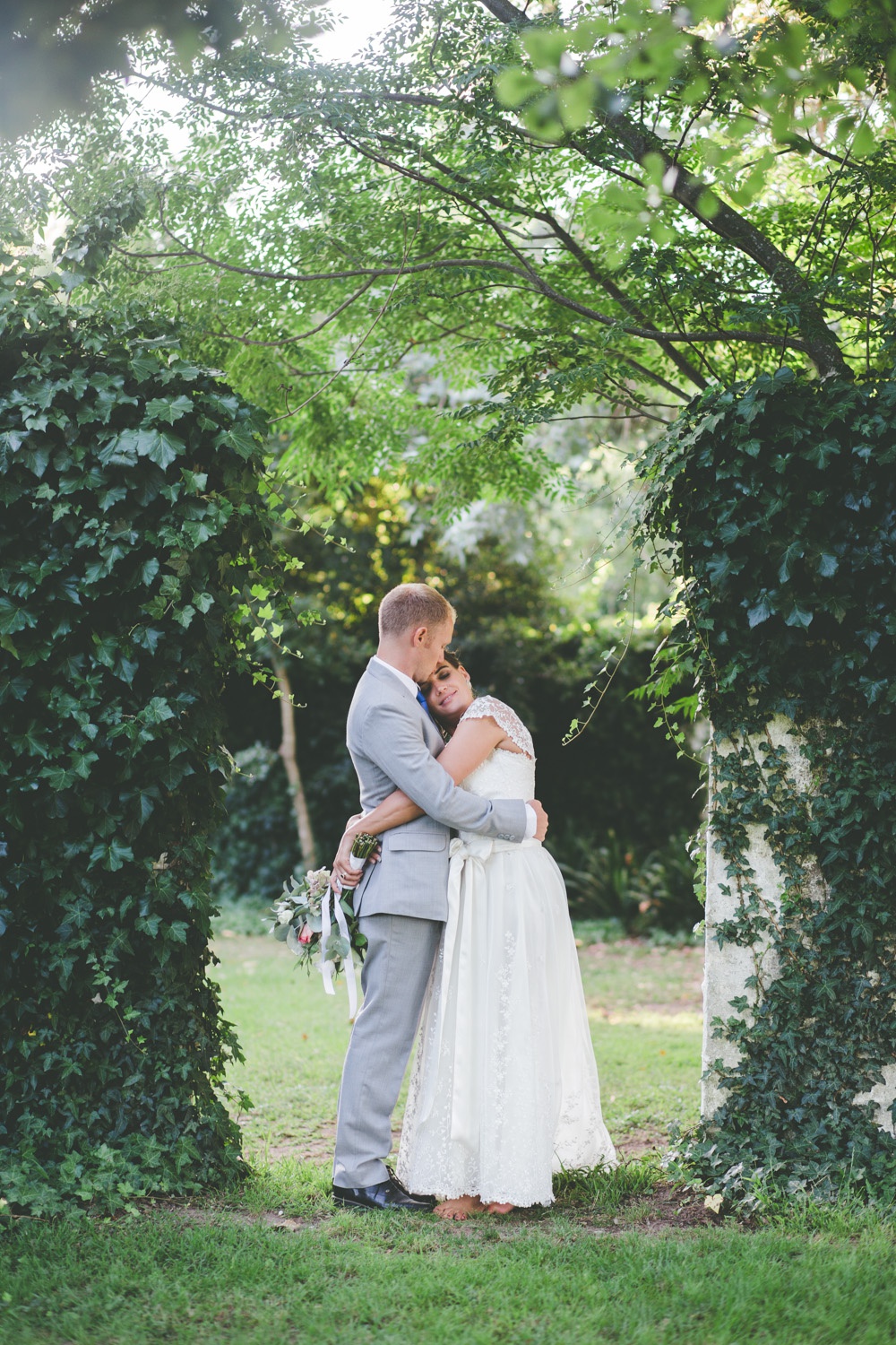 A bride standing beneath a green ivy-covered archway in the garden at Muldersvlei