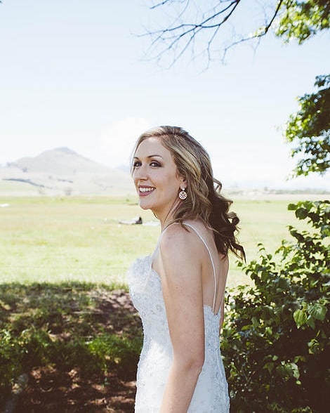 A bride looking back over her shoulder on the edge of the lands at Muldersvlei, the Simonsberg behind her