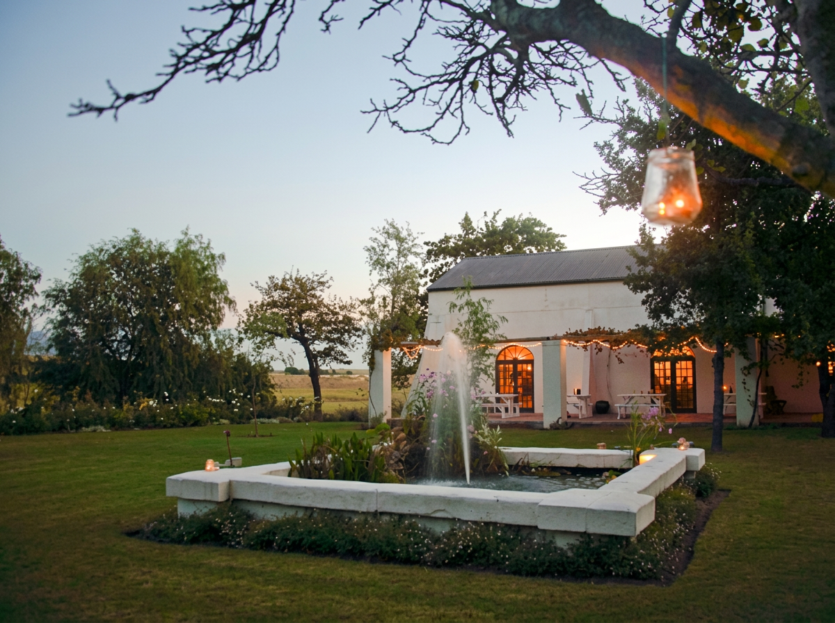 The Muldersvlei fountain, veranda and lantern-lit lawn at dusk