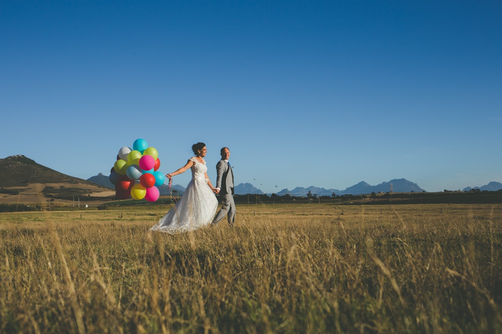 A couple in the open fields at Muldersvlei with the Simonsberg mountain behind them