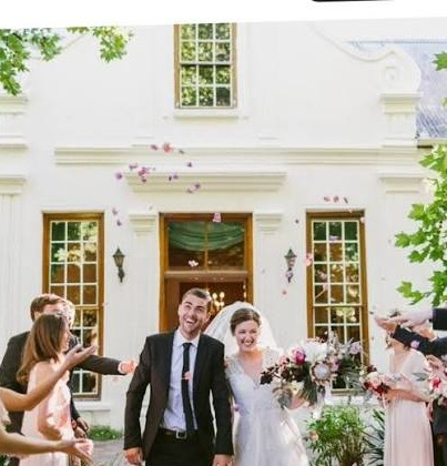 A couple leaving through the manor doorway at Muldersvlei under a shower of confetti