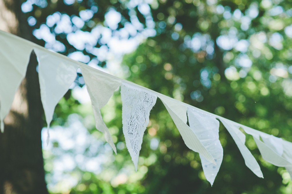 Hand-cut lace and linen bunting hanging between the oak trees