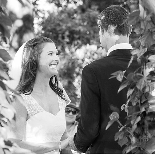 A bride laughing during her vows under the trees at Muldersvlei, black and white