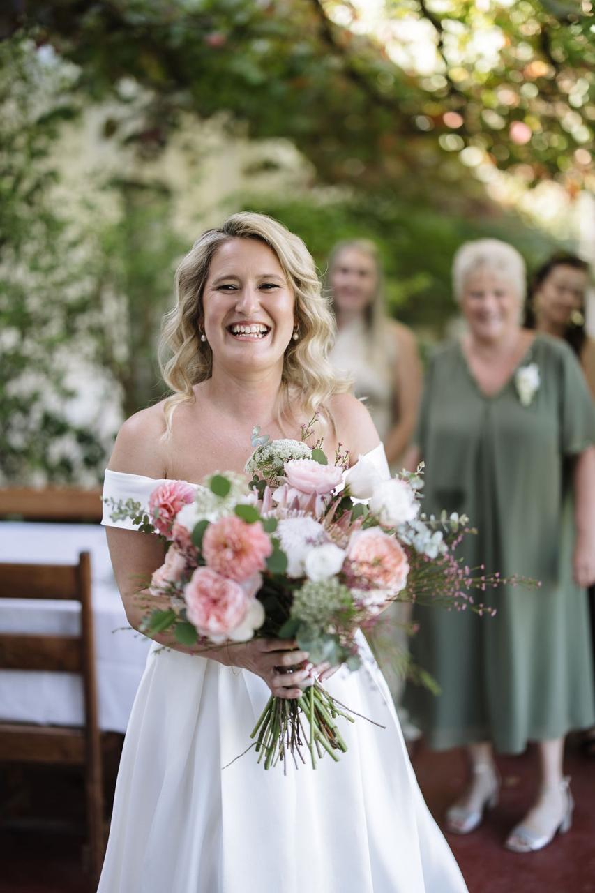 A bride walking down the grass aisle carrying her bouquet